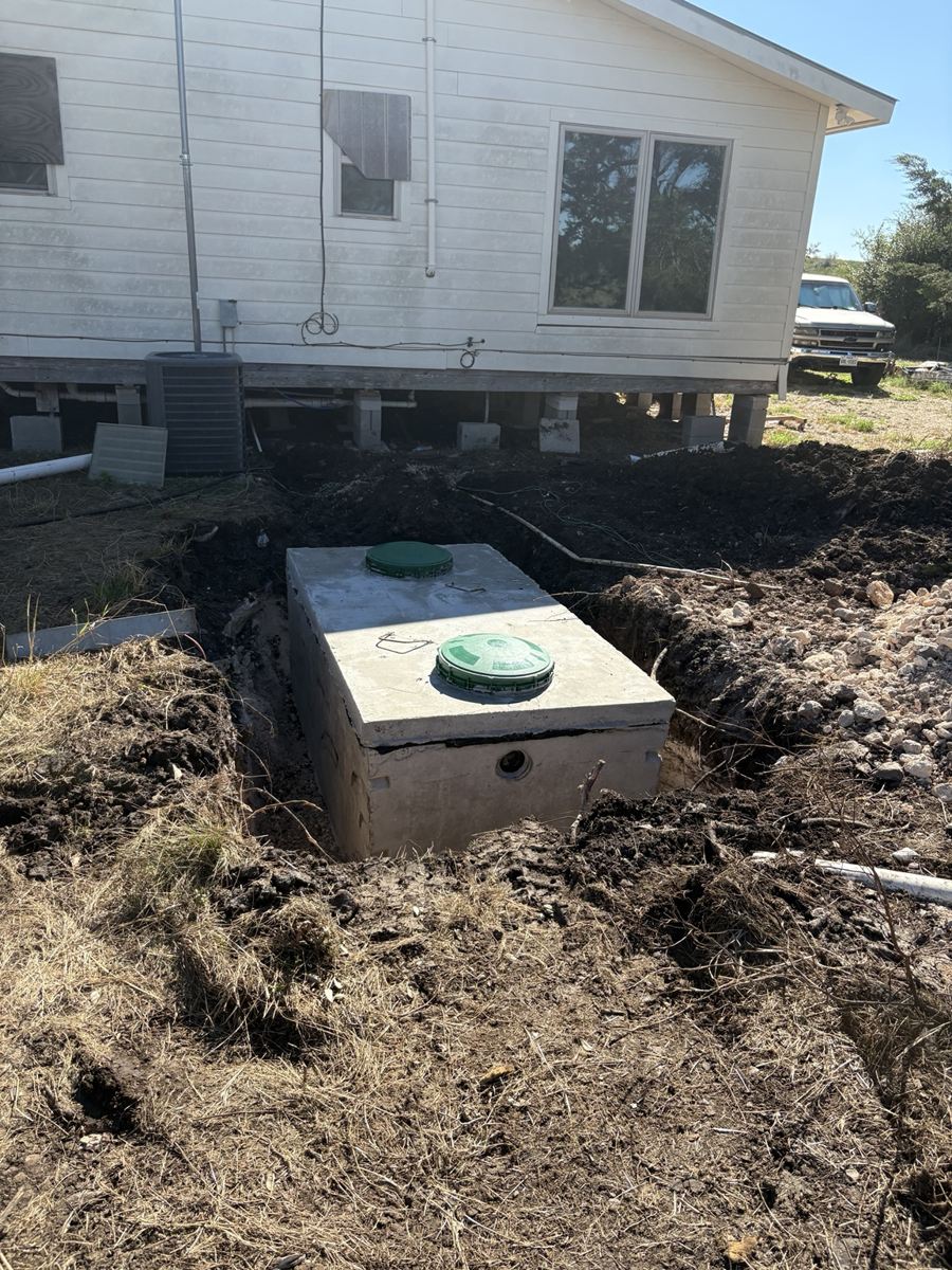 Concrete septic tank being installed beside a house
